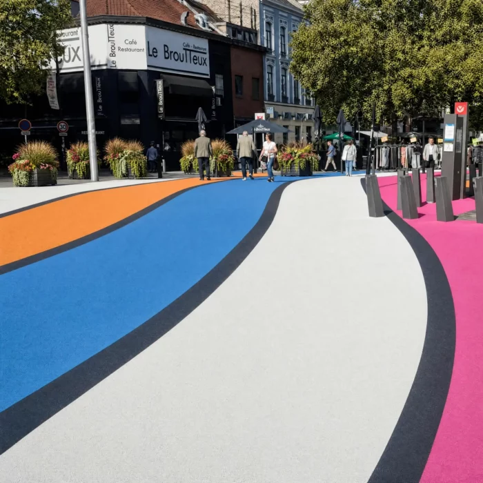 Rue piétonne moderne avec design actif coloré, bacs de fleurs luxuriants, zone d'ombre et mobilier urbain adapté aux PMR, piétons, cyclistes et vélo.
